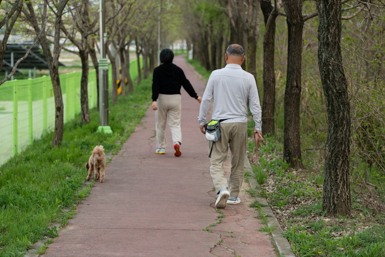 Pareja paseando a su perro por un sendero al aire libre